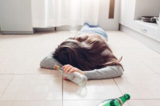 Woman on the floor with empty alcohol bottles